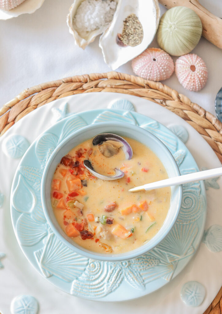 small bowl of chowder with white spoon in bowl and nautical plates underneath