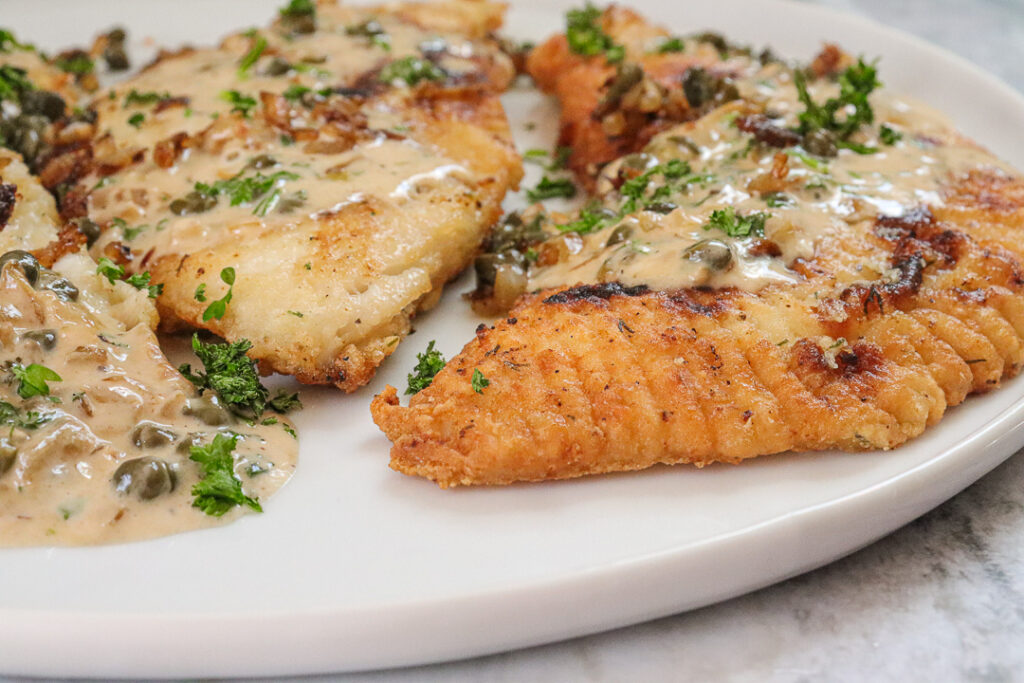 closeup cape piccata sauce over breaded skate